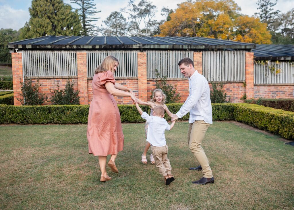 family playing ring-a-rosy in the park during a lifestyle family photography session in Ipswich